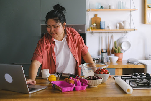 A woman using a laptop for a restaurant online ordering system for food delivery.